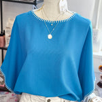 Blue sweater on a mannequin with a blurred store background
