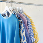 Colorful shirts hanging on a rack against a white wall