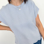 Woman wearing a light blue striped top and jeans against a white background