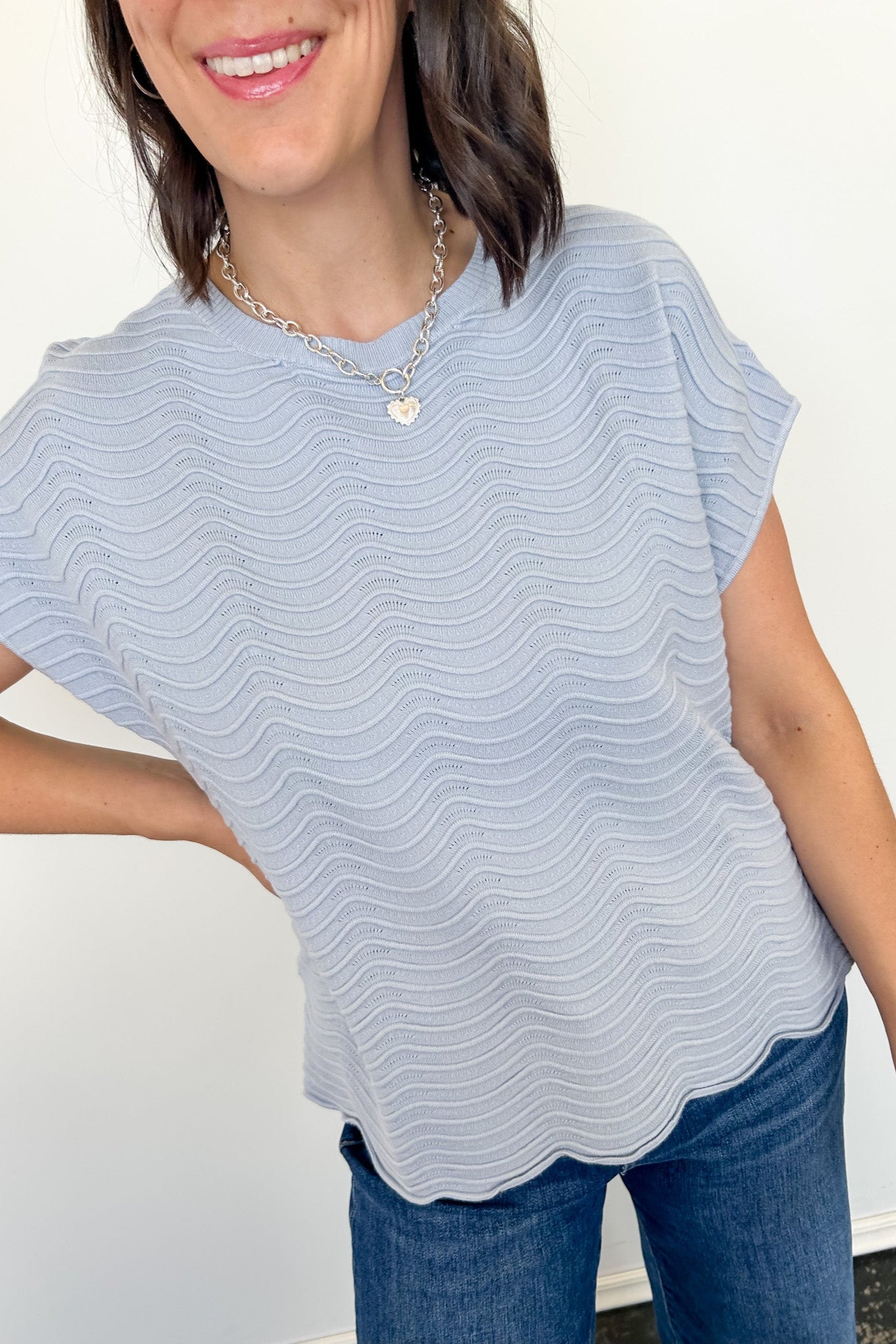 Woman wearing a light blue striped top and jeans against a white background