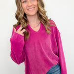Woman wearing a bright pink sweater and blue jeans against a white background