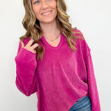 Woman wearing a bright pink sweater and blue jeans against a white background