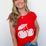 Woman wearing a red sleeveless top with white cherries on a plain background