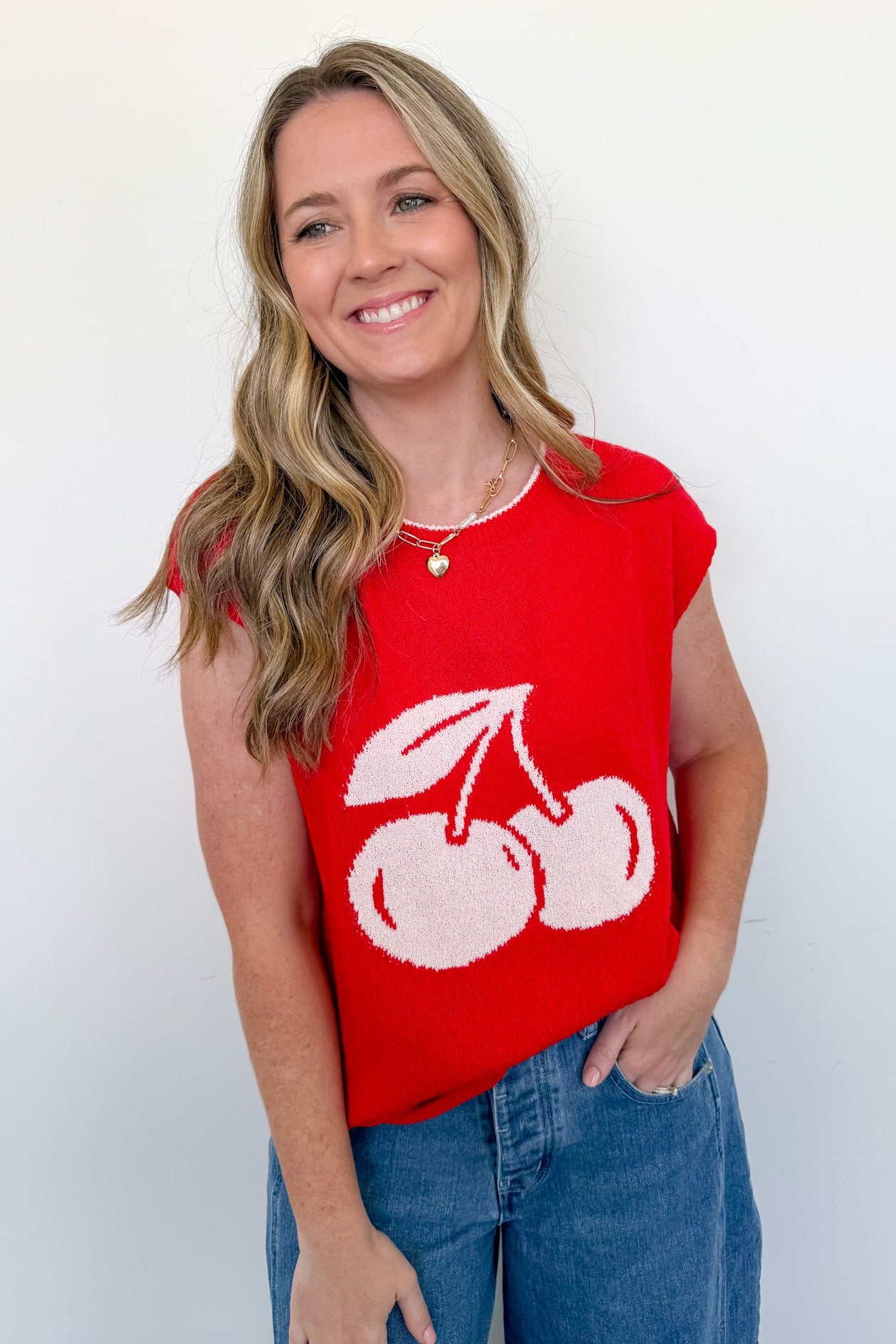 Woman wearing a red sleeveless top with white cherries on a plain background