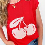 Red sleeveless top with white cherry design worn by a person against a white background