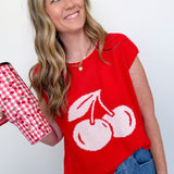 Woman wearing a red shirt with white cherries holding a red and white checkered mug.