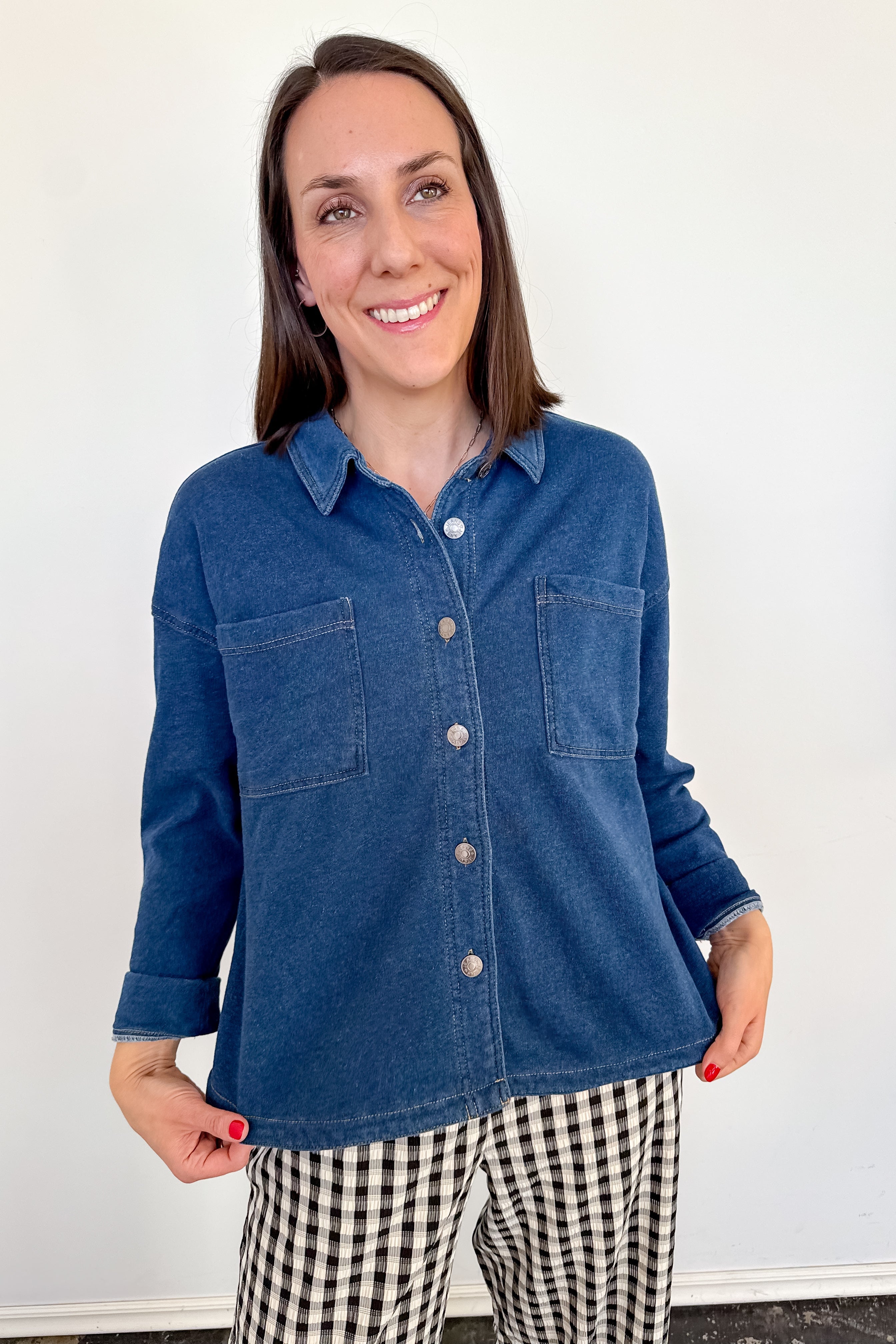 Woman wearing a blue denim shirt and checkered pants against a white background