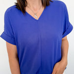 Woman wearing a blue top and white shorts against a plain background