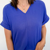 Woman wearing a blue top and white shorts against a plain background