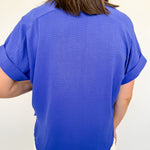 Person wearing a blue shirt and white shorts against a plain background