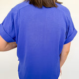 Person wearing a blue shirt and white shorts against a plain background
