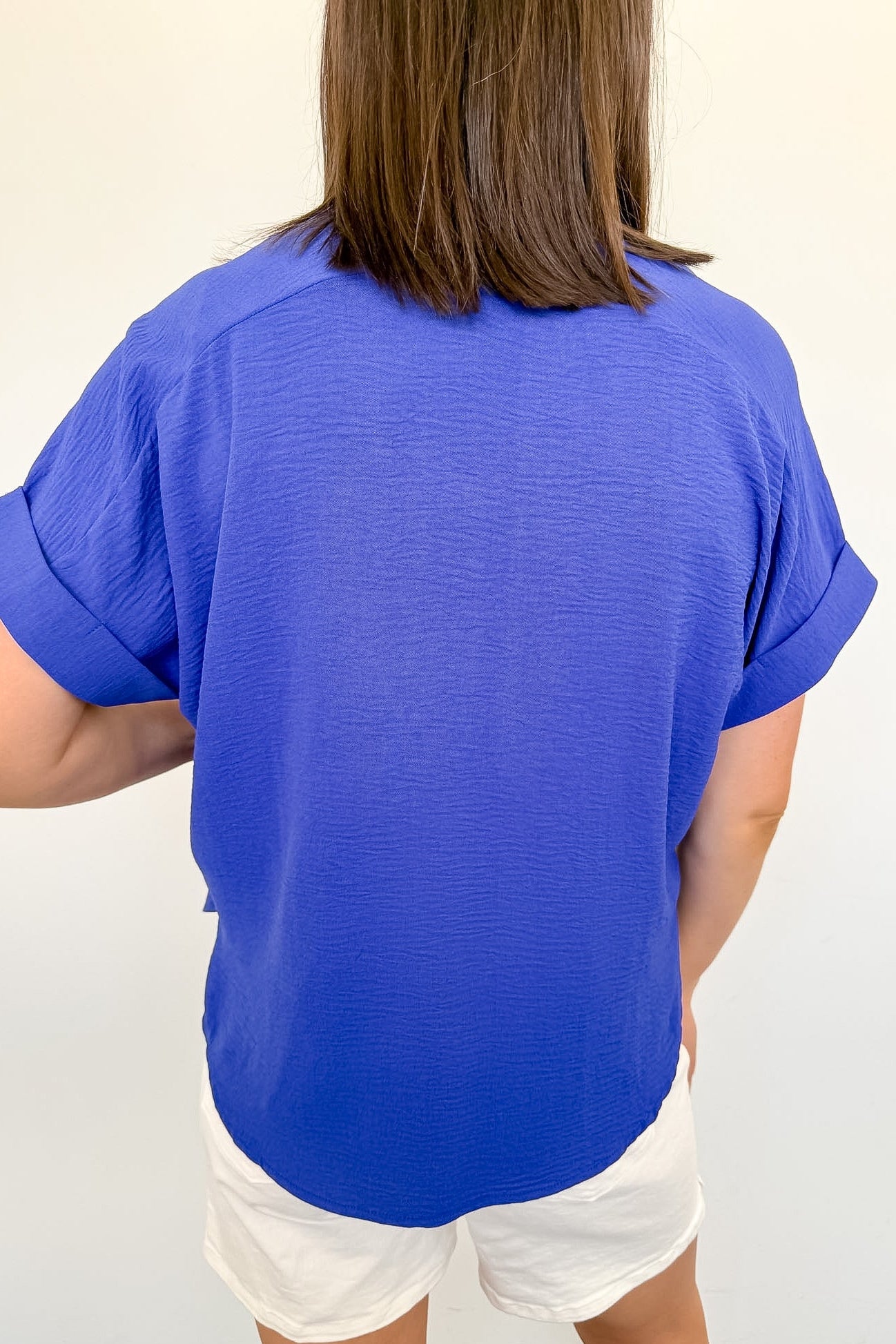 Person wearing a blue shirt and white shorts against a plain background