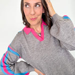 Woman wearing a gray sweater with pink and blue accents on a white background
