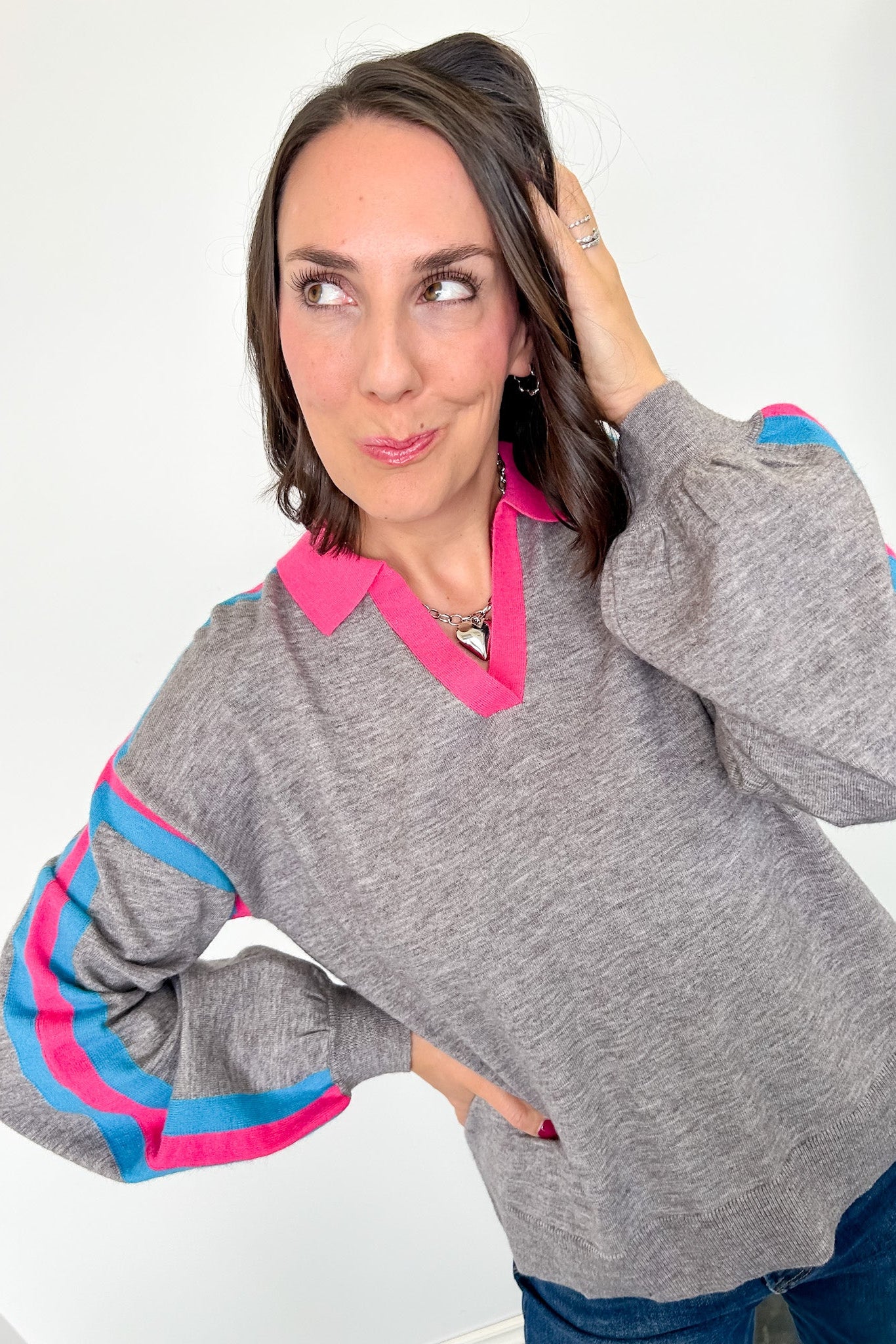 Woman wearing a gray sweater with pink and blue accents on a white background