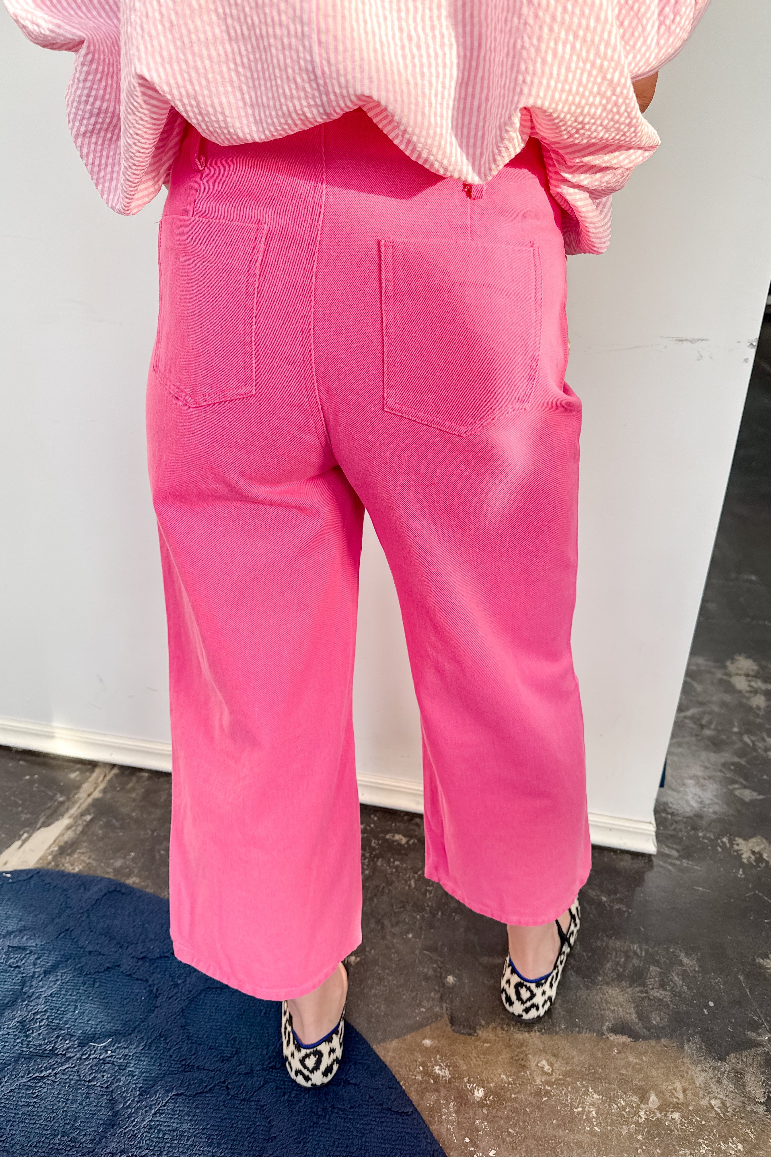 Person wearing pink pants and a checkered shirt in an indoor setting.