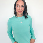 Woman wearing a light blue long-sleeve shirt against a white background