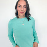 Woman wearing a light blue long-sleeve shirt against a white background