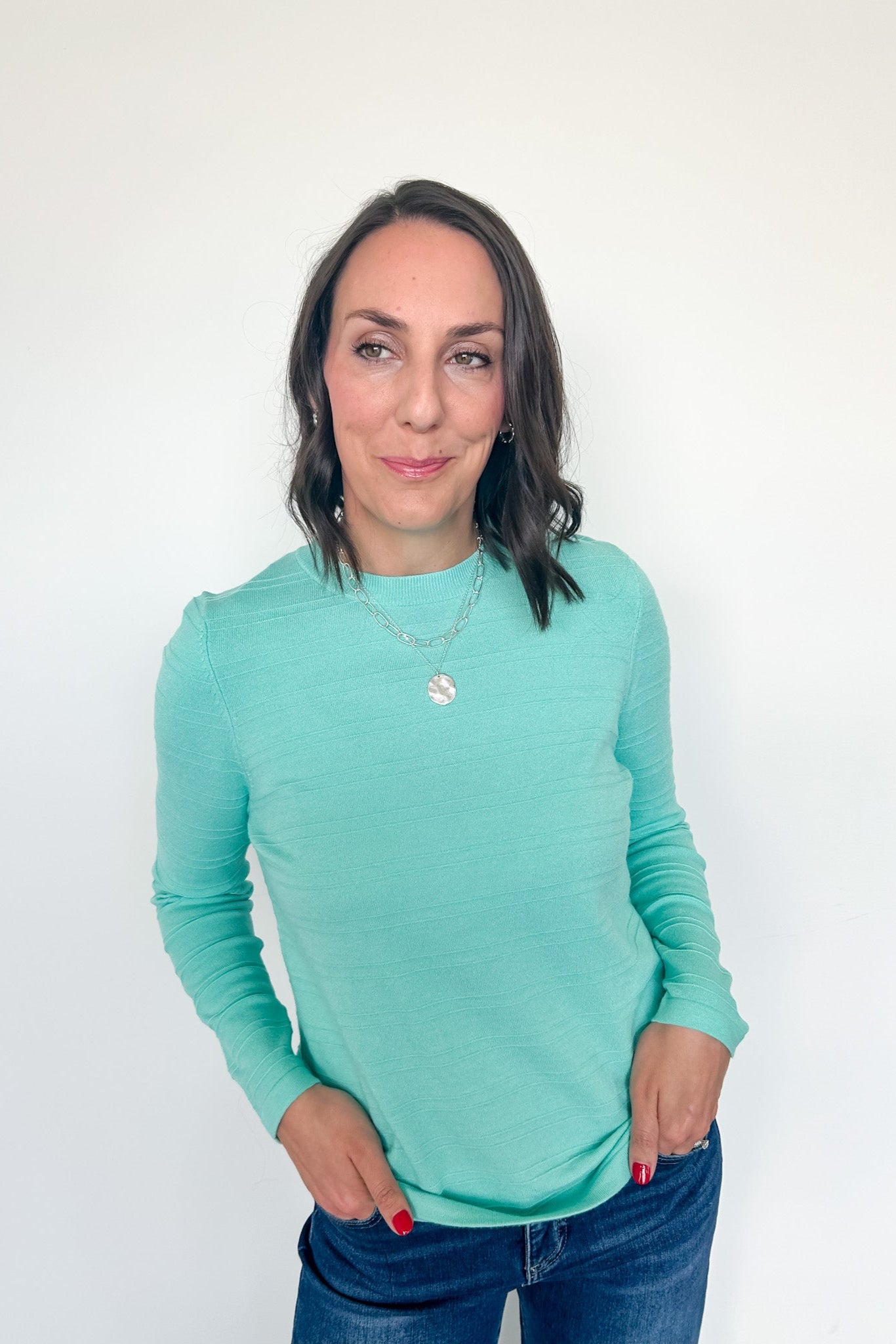 Woman wearing a light blue long-sleeve shirt against a white background