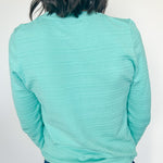 Person wearing a light blue long-sleeve shirt and jeans against a white background