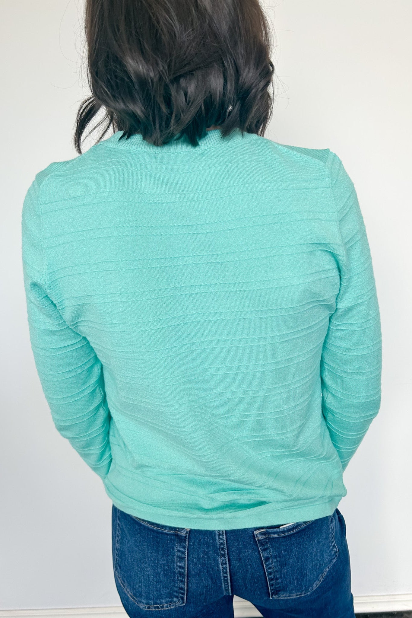 Person wearing a light blue long-sleeve shirt and jeans against a white background