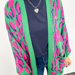 Person wearing a colorful cardigan with pink and green patterns on a white background