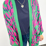 Person wearing a colorful cardigan with pink and green patterns on a white background