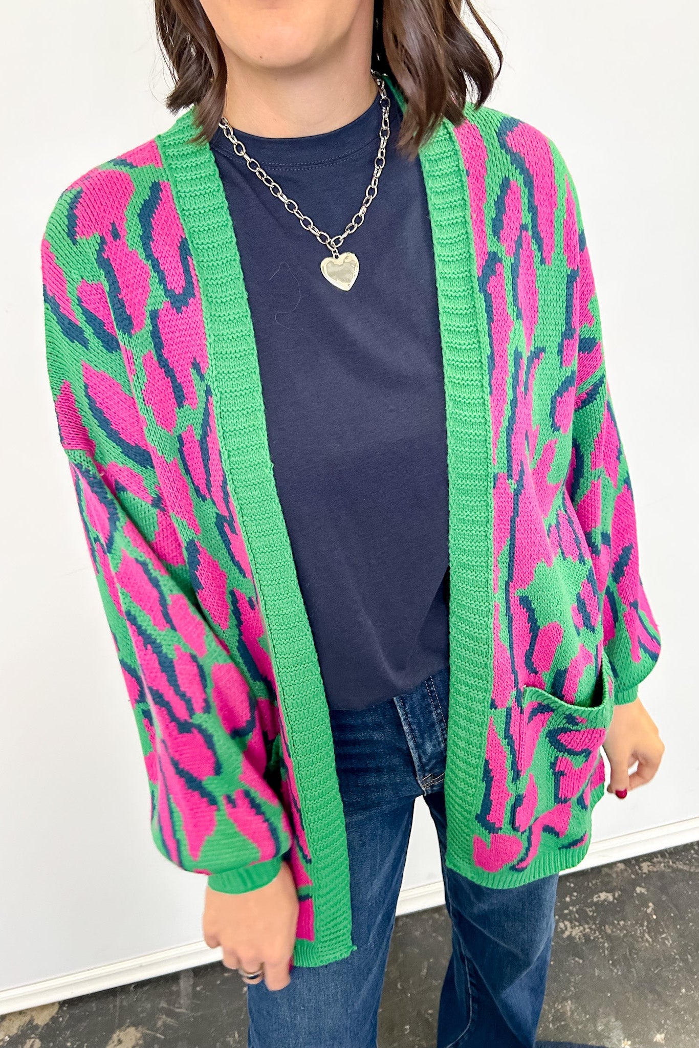 Person wearing a colorful cardigan with pink and green patterns on a white background