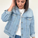Woman wearing light wash denim jacket with white tee underneath.