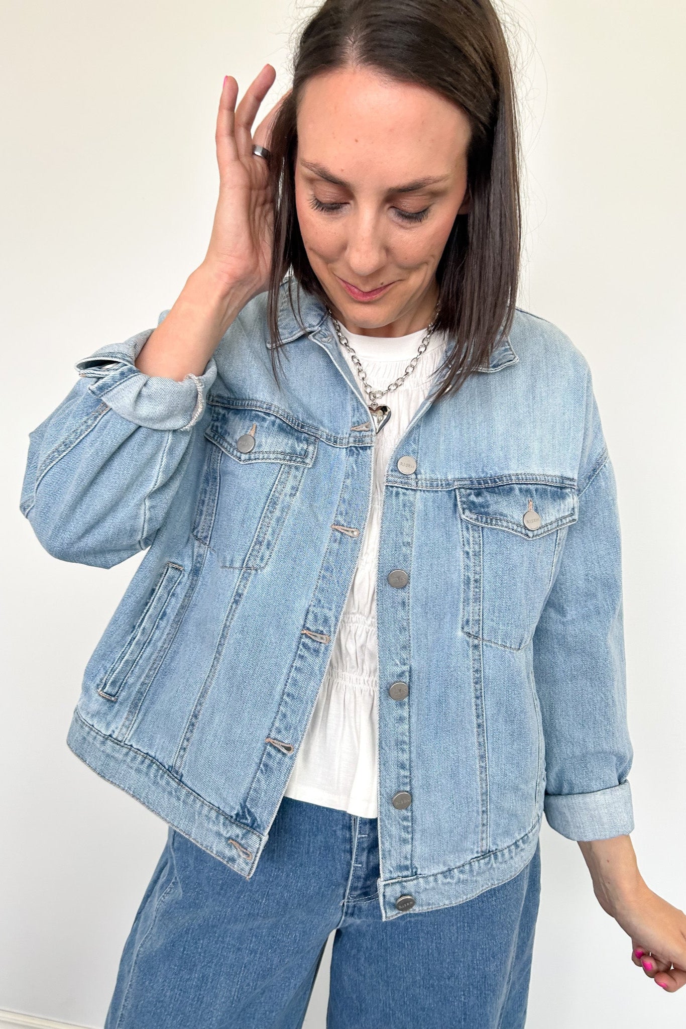 Woman wearing light wash denim jacket with white tee underneath.