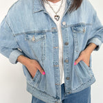 Person wearing a light blue denim jacket and jeans on a white background