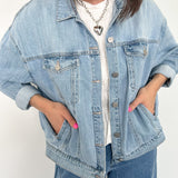 Person wearing a light blue denim jacket and jeans on a white background