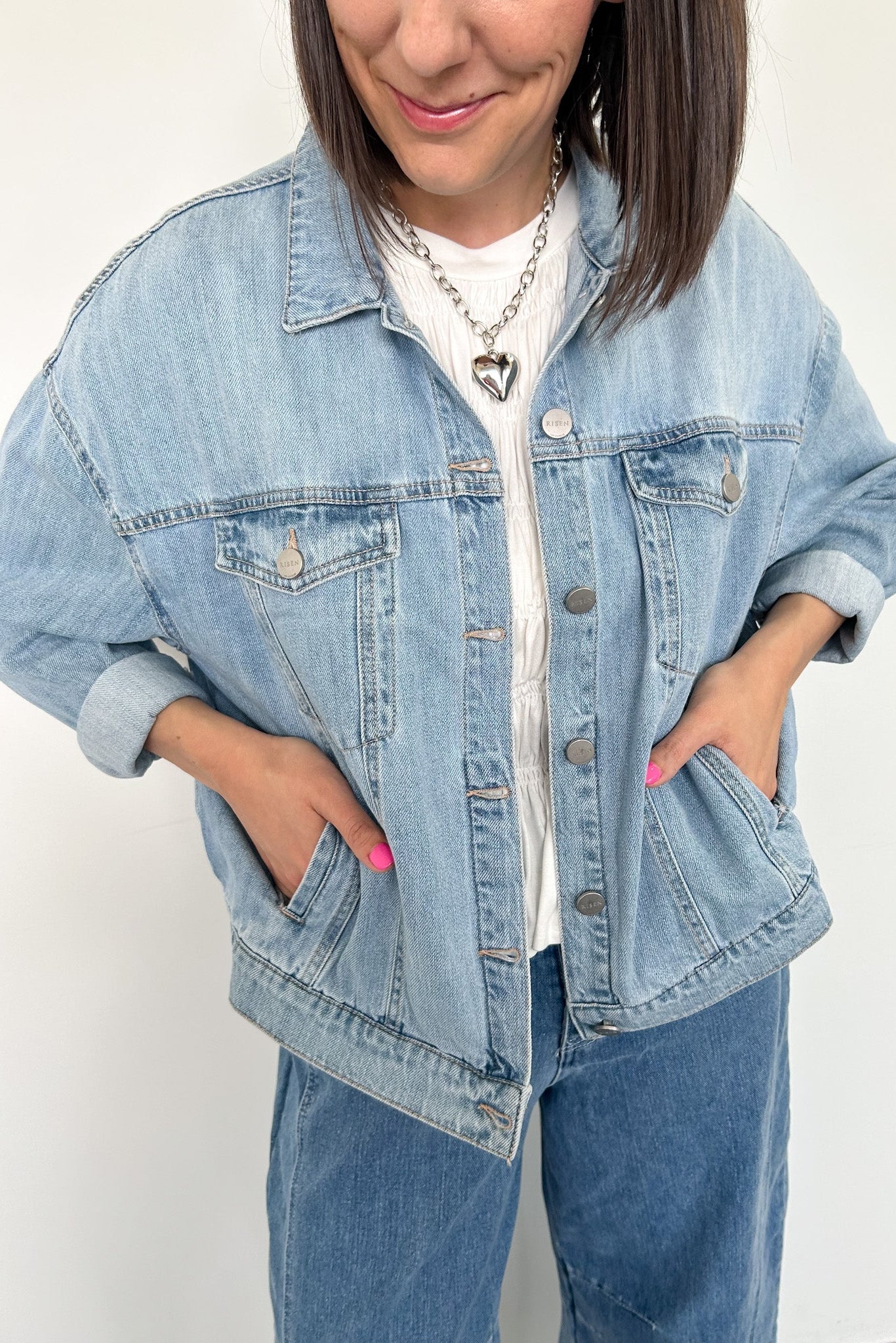 Person wearing a light blue denim jacket and jeans on a white background