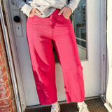 Person wearing a gray sweater and pink pants standing in front of a door.