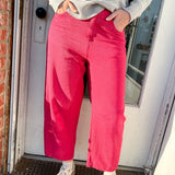 Person wearing a gray sweater and pink pants standing in front of a door.