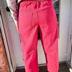Person wearing bright pink pants standing in front of a door.