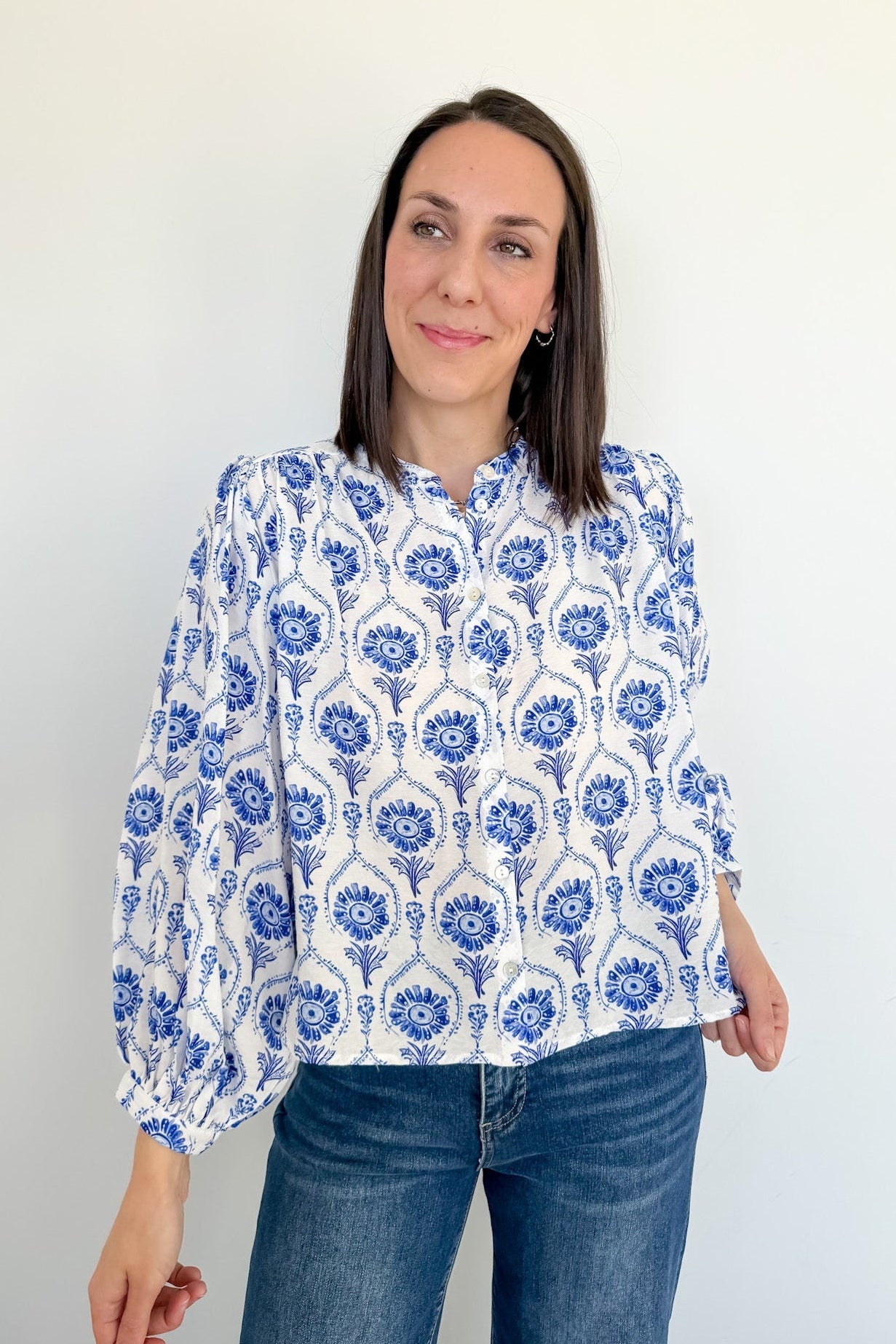 Woman wearing a blue and white patterned blouse against a plain background