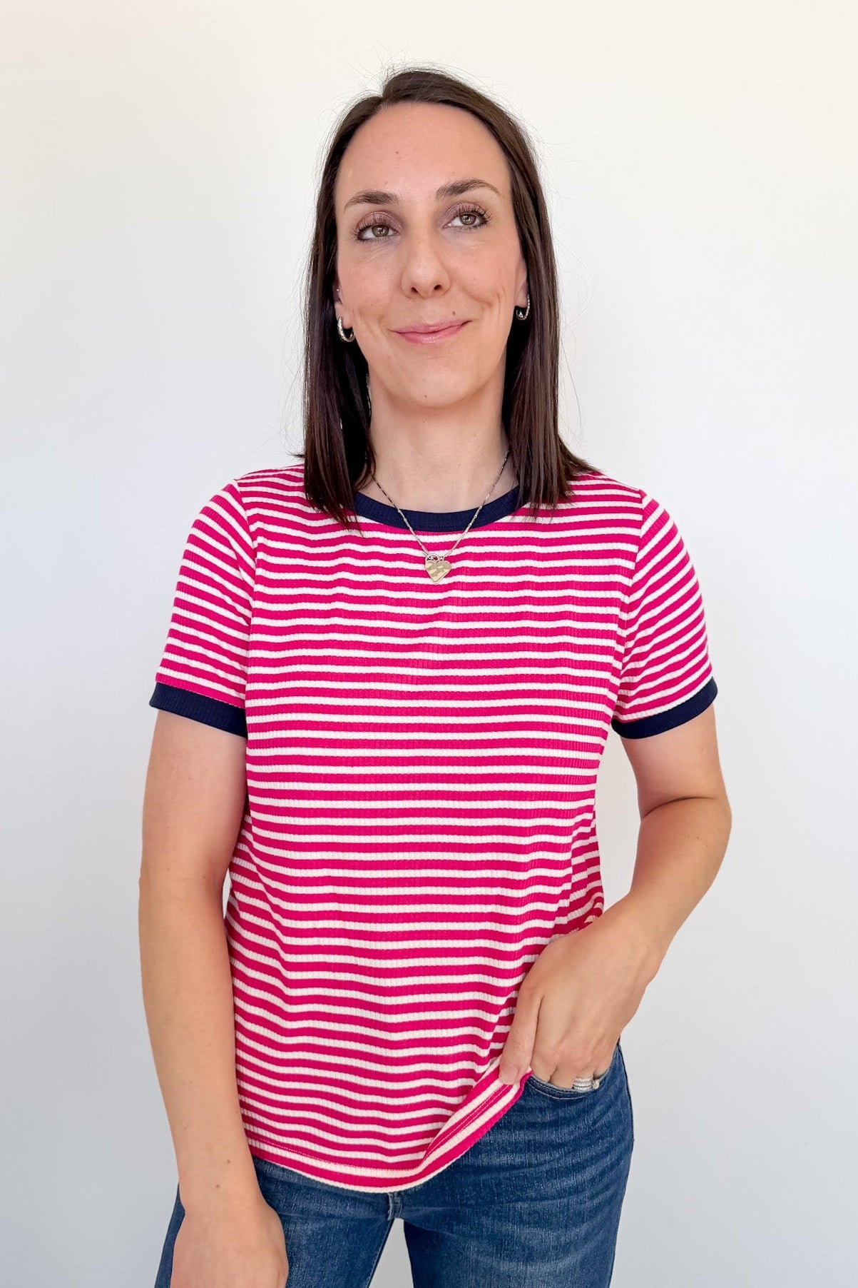 Woman wearing a pink and white striped shirt against a plain background