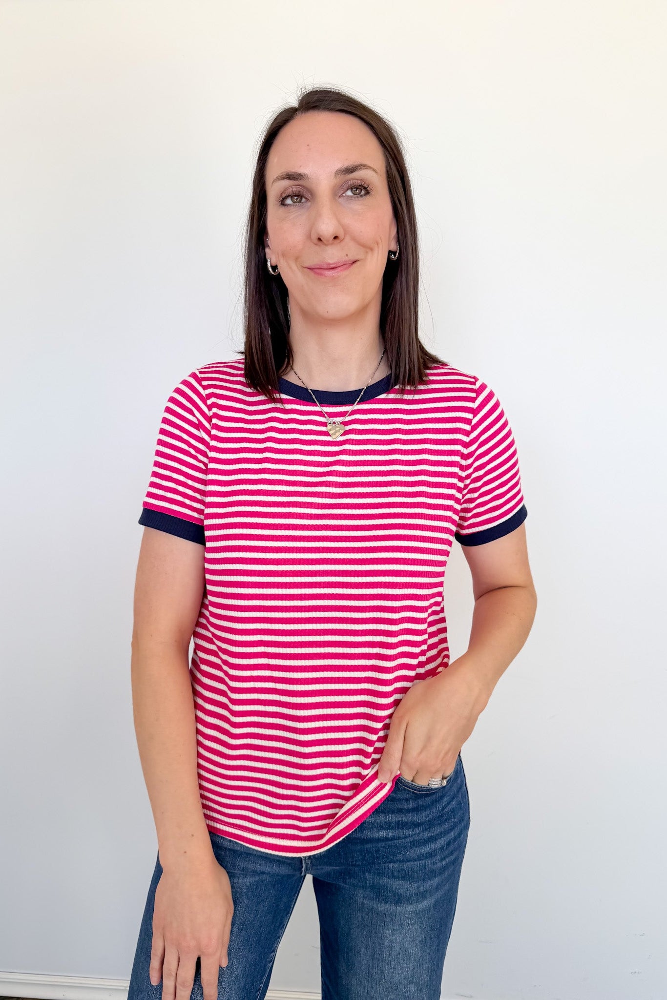 Woman wearing a pink and white striped shirt against a plain background