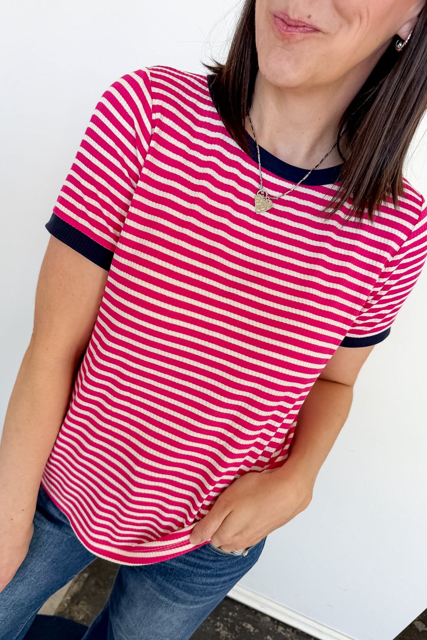 Person wearing a red and white striped shirt with blue jeans against a white background