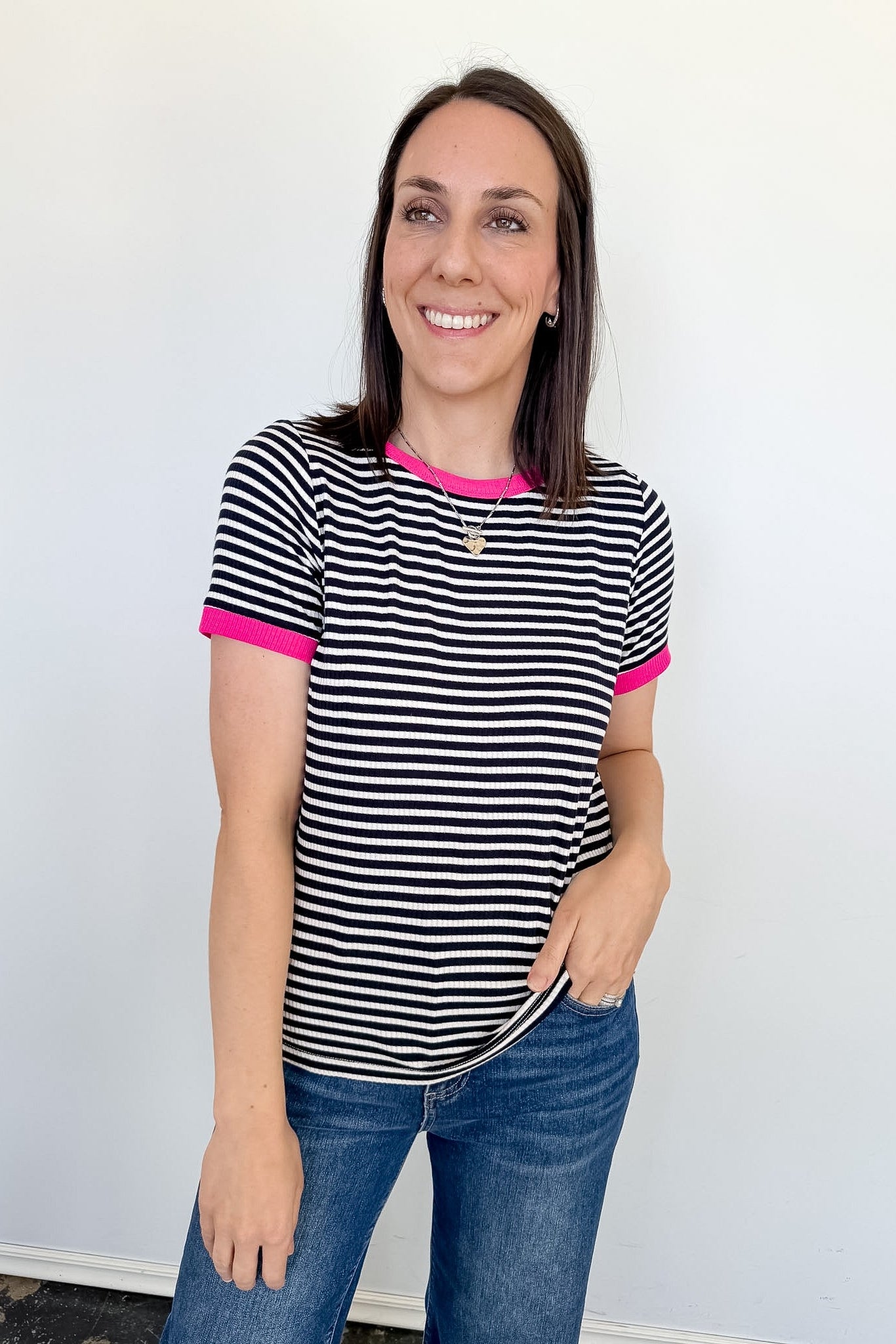 Woman wearing a black and white striped shirt with pink accents against a white background