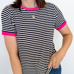 Woman wearing a black and white striped shirt with pink trim against a white background