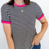 Woman wearing a black and white striped shirt with pink trim against a white background