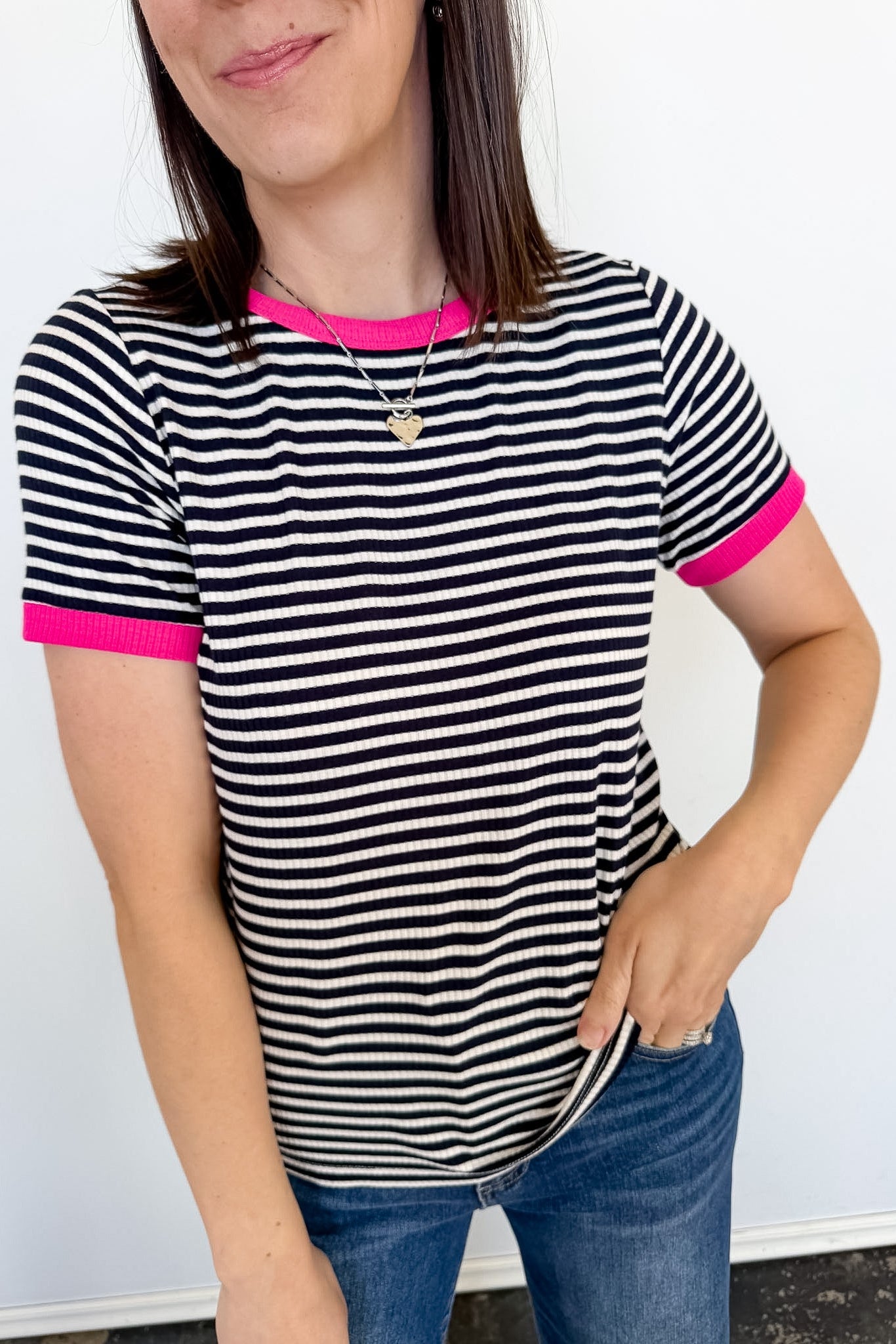 Woman wearing a black and white striped shirt with pink trim against a white background