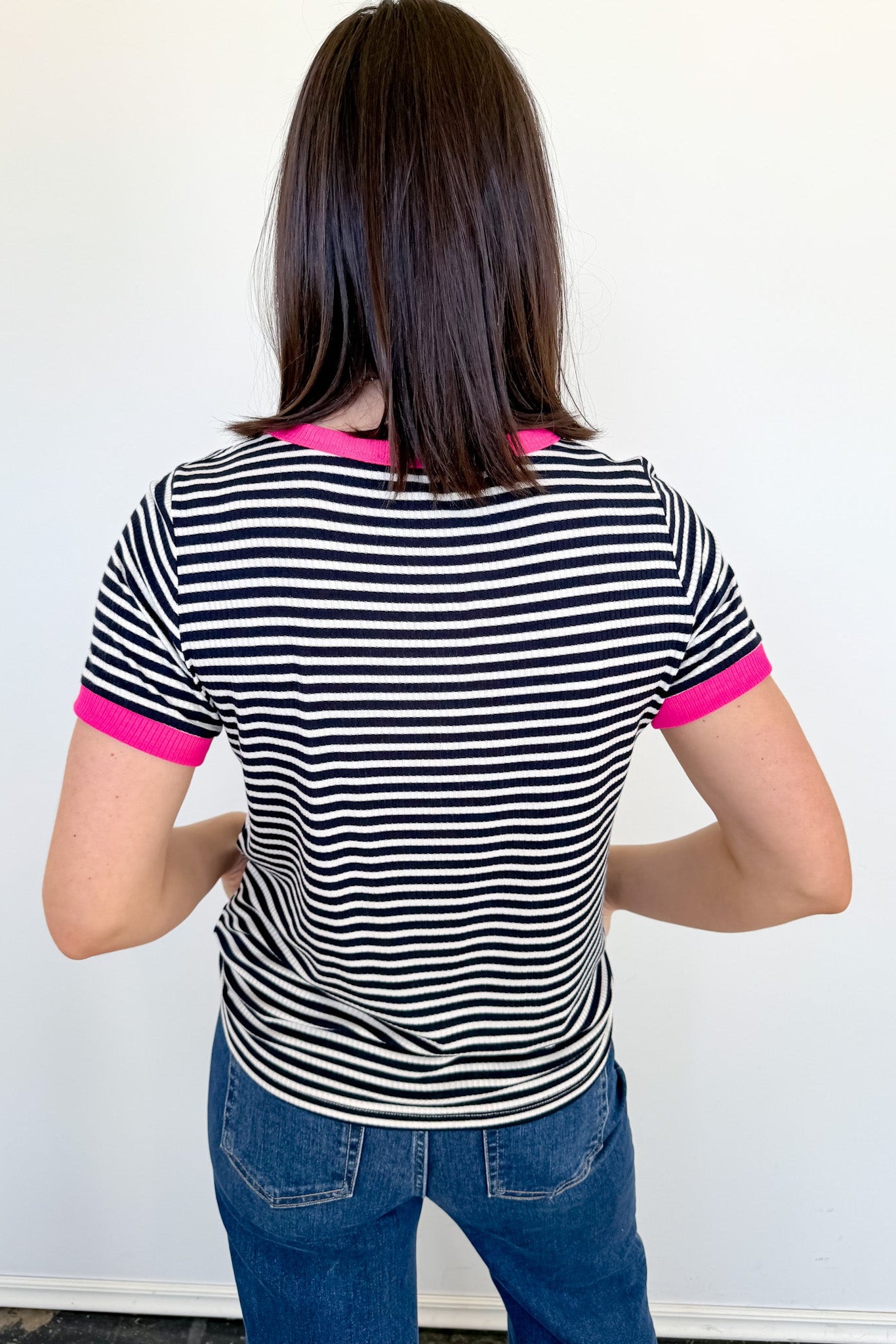 Person wearing a black and white striped shirt with pink trim against a white background