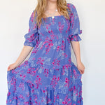 Flowy floral print dress with colors periwinkle and hot pink. Smocked bodice. Puff sleeves with tiered bottom. 