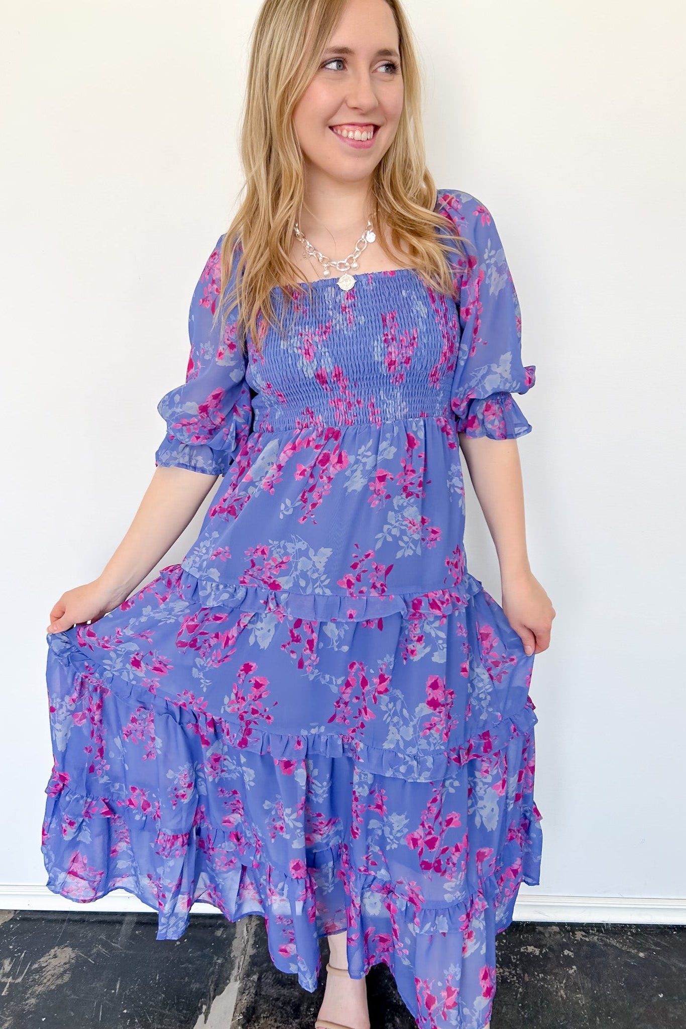 Flowy floral print dress with colors periwinkle and hot pink. Smocked bodice. Puff sleeves with tiered bottom. 