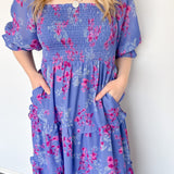Flowy floral print dress with colors periwinkle and hot pink. Smocked bodice. Puff sleeves with tiered bottom. 