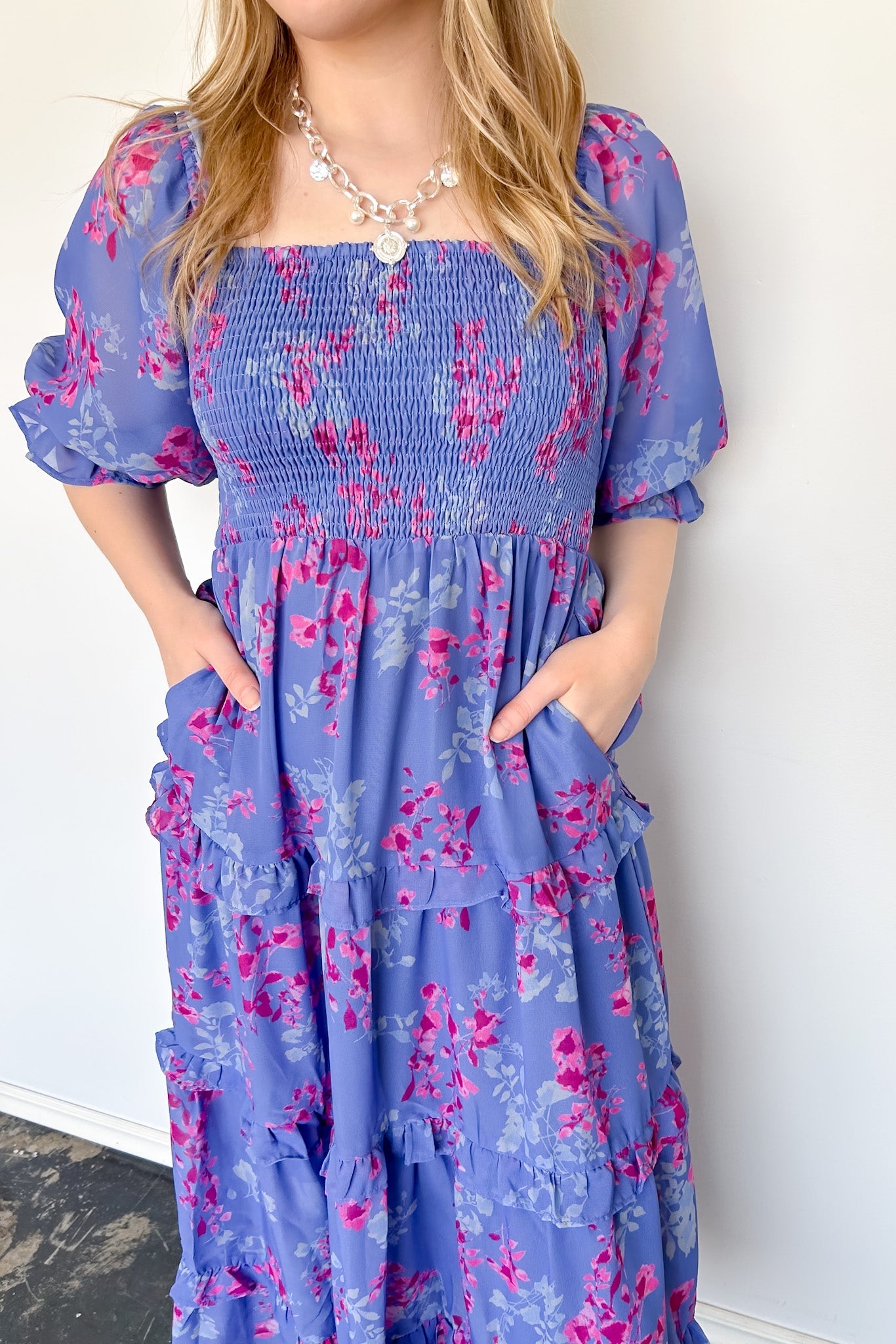 Flowy floral print dress with colors periwinkle and hot pink. Smocked bodice. Puff sleeves with tiered bottom. 