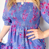 Flowy floral print dress with colors periwinkle and hot pink. Smocked bodice. Puff sleeves with tiered bottom. 