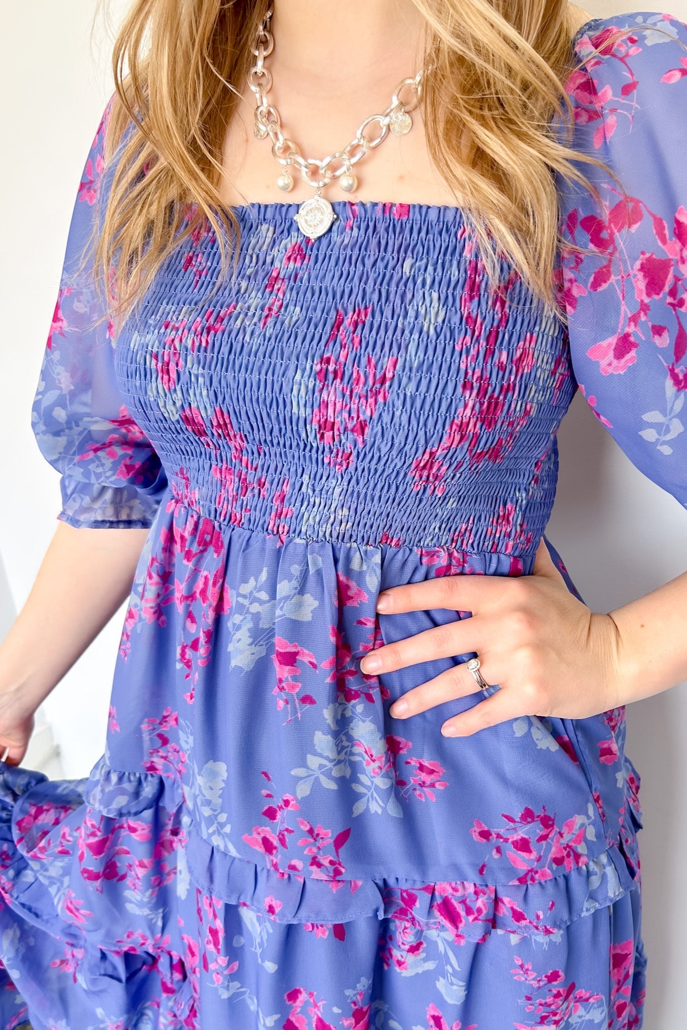Flowy floral print dress with colors periwinkle and hot pink. Smocked bodice. Puff sleeves with tiered bottom. 